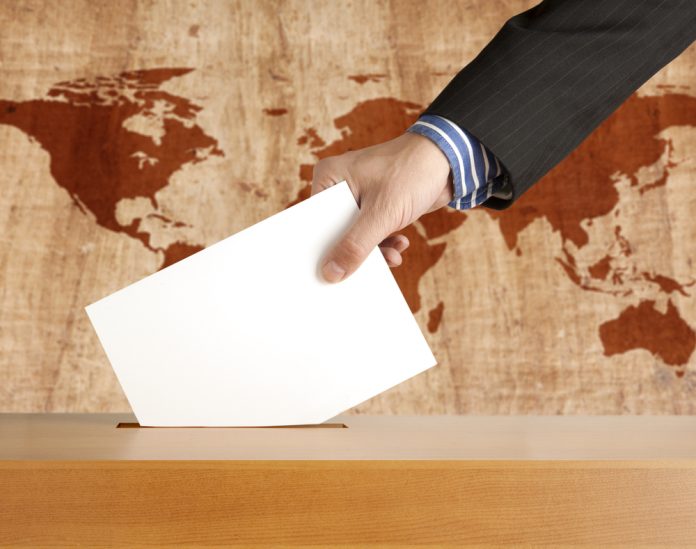 Hand,Putting,A,Voting,Ballot,In,A,Slot,Of,Box Seçim sandığı dünyayı durdurmuyor